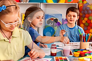 Small students girl painting in art school class.