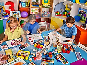 Small students girl painting in art school class.