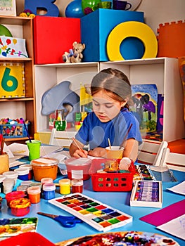 Small students girl painting in art school class.