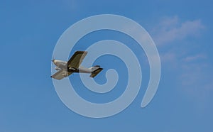 Small stunt airplane flying in a clean blue sky, air transportation, hobbies and sports