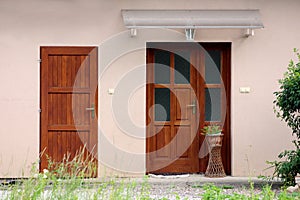 Small suburban family house new rustic looking wooden entrance doors with flower pot and red flowers covered with transparent