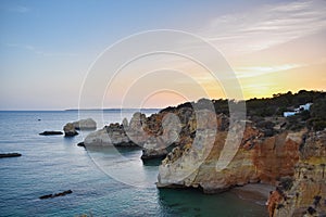 Small summer house on top of the cliffs, overlooking the sea, at sunset. Algarve, Portugal