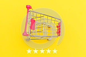 Small supermarket grocery push cart for shopping toy with wheels and 5 stars rating isolated on yellow background. Retail consumer