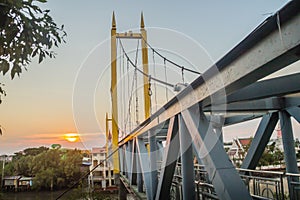 Small suspension steel bridge structure detail. Steel structure support of the suspension bridge across the river with sunset and