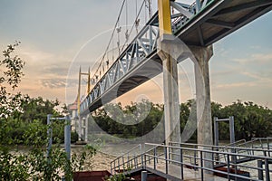 Small suspension steel bridge structure detail. Steel structure support of the suspension bridge across the river with sunset and