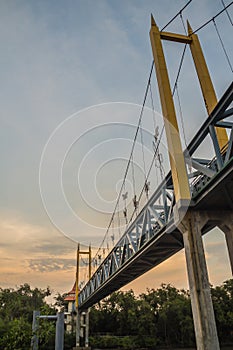 Small suspension steel bridge structure detail. Steel structure support of the suspension bridge across the river with sunset and