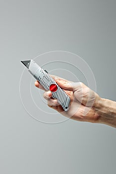 Small Swiss knife in male hands isolated on gray
