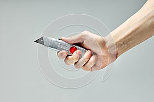 Small Swiss knife in male hands isolated on gray