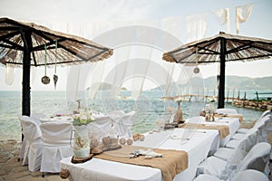 small tables under parasols await the lucky guests of this intimate wedding by the sea