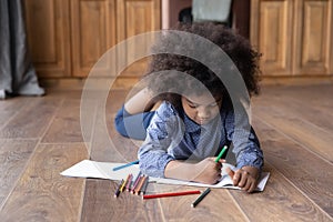 Small teen ethnic girl drawing in album at home