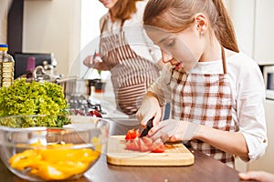 Small teenage girl cutting tomatoes in salad