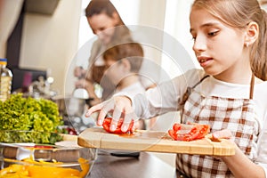 Small teenage girl cutting tomatoes in salad