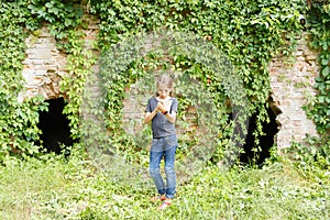 Small teenage girl standing near old brick ruins
