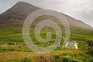 Small tent set up in a field, Smoke coming out from chimney, Mountain in fog in the background, Low clouds, Connemara, Ireland,