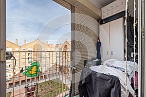 A small terrace of a house with a clothesline full of clothes and a metal railing