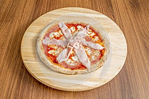 Small thin crust pizza with mozzarella cheese and lots of cooked ham