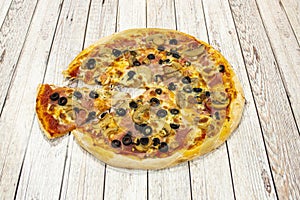 Small thin crust pizza with slices of black olives, slices of mushroom, cooked ham, oregano and a portion stretching