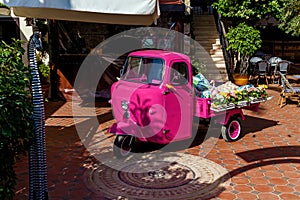 A small three-wheeled car stands on the empty street