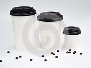 From small to big a line of white paper cups with coffee beans isolated on white. Coffee shop mockup with copyspace