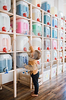 A small toddler boy standing by dispensers in zero waste shop. photo