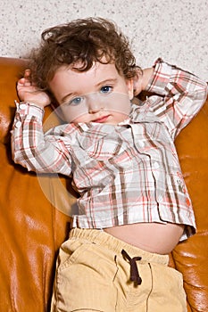 small toddler with on a leather brown sofa