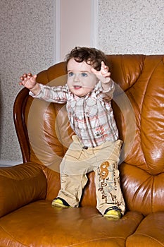 The small toddler on a leather brown sofa stretc