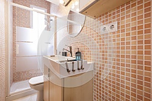 Small toilet with white porcelain sink, square shower with pink tiles