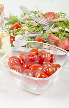 Small tomatoes in a glass jar with salad