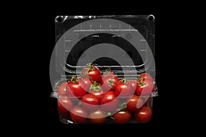 Small tomatoes in plastic packaging on a black background