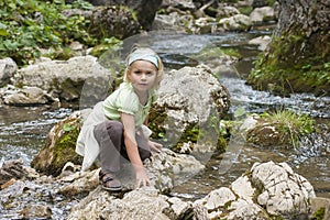 Small tourist sitting by a mountain river