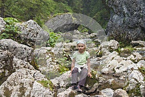 Small tourist sitting by a mountain river