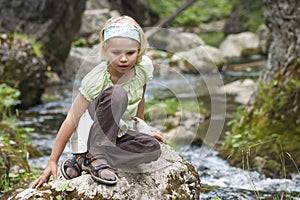 Small tourist sitting by a mountain river