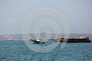 Small towing tugboat dragging the huge Dredger ship in the sea. Drilling industry in the ocean. image for background,