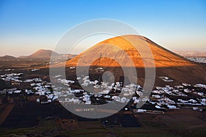 The small town Monte Guatisea at the foot of the volcano Montana Blanca. Sunset, the mountain is in the last sunlight. Lanzarote,