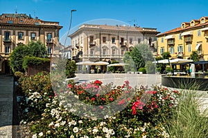 Small town square among buildings and flowers in Alba, Italy