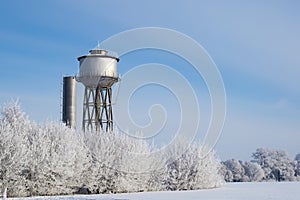 Small town water tower, lit by sunlight against a frozen landscapes.