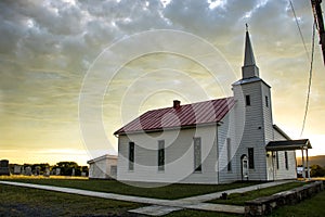 Small town church and cemetery with sun lite clouds photo
