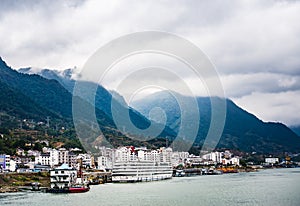 Small town at Yangtze river`s edge with mountain and cloud background