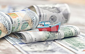 A small toy boat overcomes waves of dollar bills