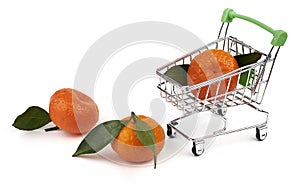 Small toy cart for groceries from the supermarket and three tangerines with green leaves