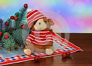 A small toy puppy in a red hat and spruce branches with red berries next to it on colorbackground