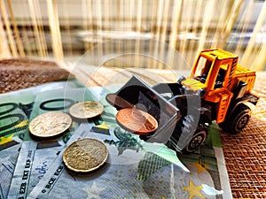 A small toy tractor or excavator on a bundle of money. The concept of the high cost of technology. The possibility of