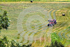 Small tractor with round baler haymaking on a field in Geiranger, Norway