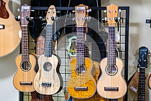 4 small traditional havaiian small acoustic guitars Ukulele hanging on a music store.