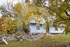 Small, traditional old country house, walnut tree in abandoned yard, cloudy autumn day, green tourism