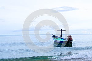 A small traditional wooden blue and green fishing boat anchoring