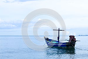 A small traditional wooden blue and green fishing boat anchoring