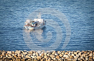 Small traditional wooden fishing motor boat floating out of small marina in Rafina, Greece