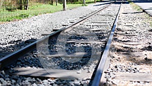 The small train track has tree shadows reflected on it