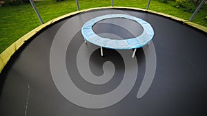 Small trampoline on big one with round mat, size comparison, green lawn background